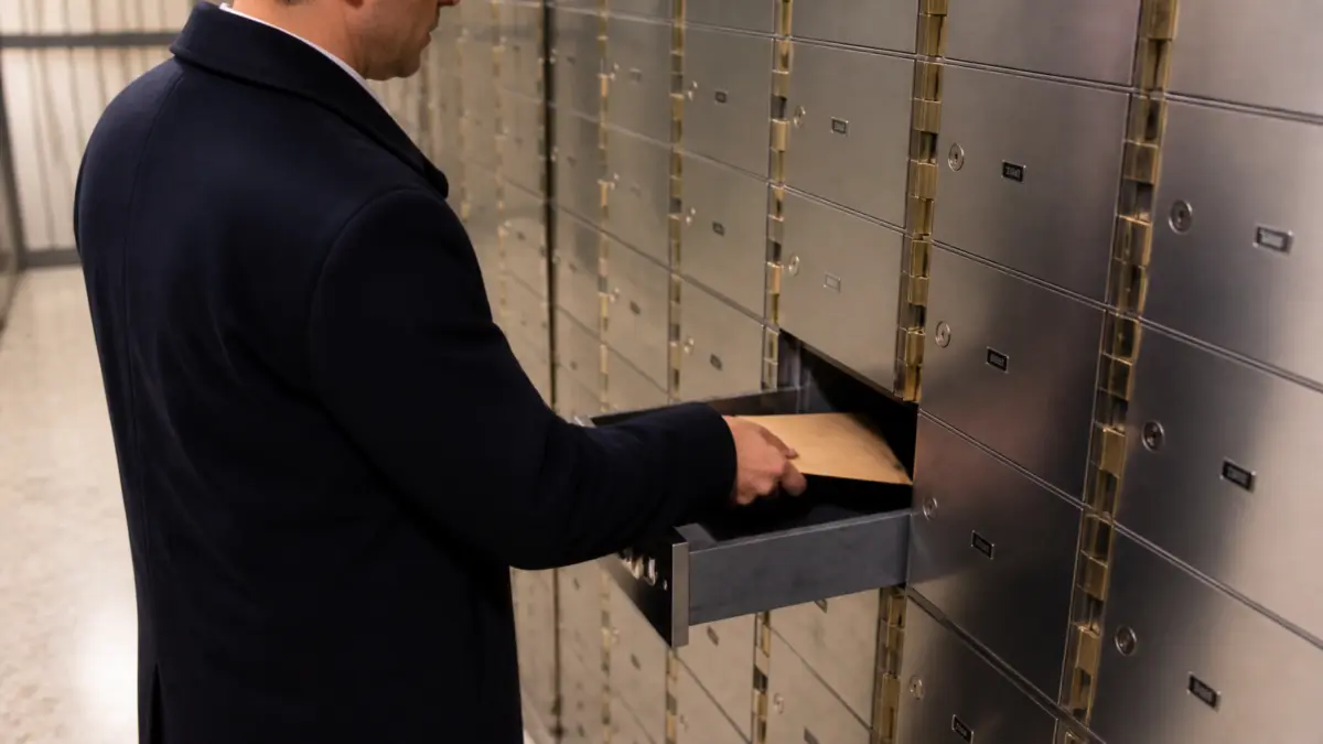 Eine Person legt einen Umschlag mit einem Wallet-Backup in ein Bankschließfach